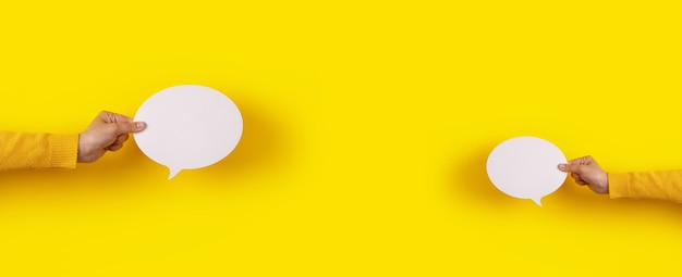 Icône de discours de deux bulles de conversation en main sur fond jaune, mise en page panoramique