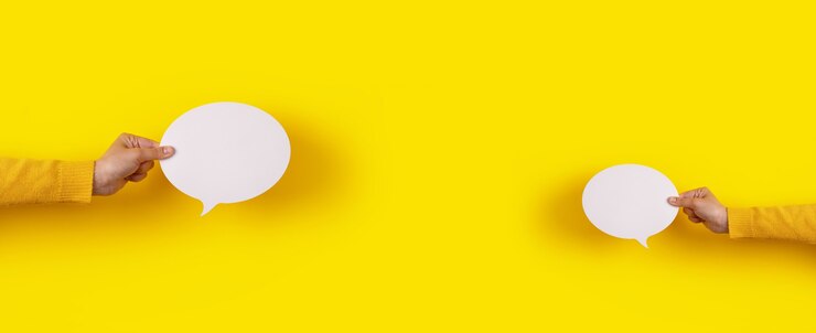 Photo icône de discours de deux bulles de conversation en main sur fond jaune, mise en page panoramique