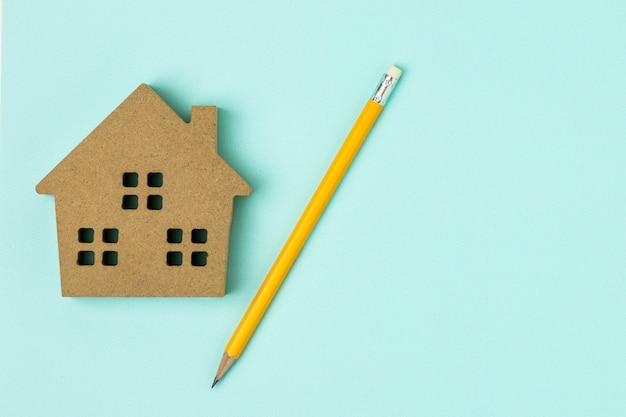 Icône de maison en bois brun et un crayon sur fond bleu