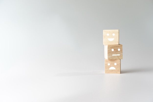 Icône de visage et panier de sourire sur le cube de bois. Personne ou personnes optimistes se sentant à l'intérieur et évaluation du service lors de l'achat, concept de satisfaction.