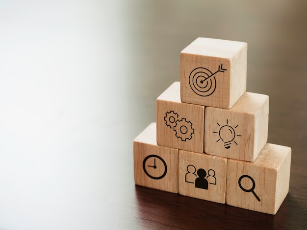 Icônes d'affaires modernes sur des blocs de cubes en bois, marches pyramidales sur le bureau avec espace de copie. Leadership, succès clé, stratégie commerciale et concept de plan d'action.