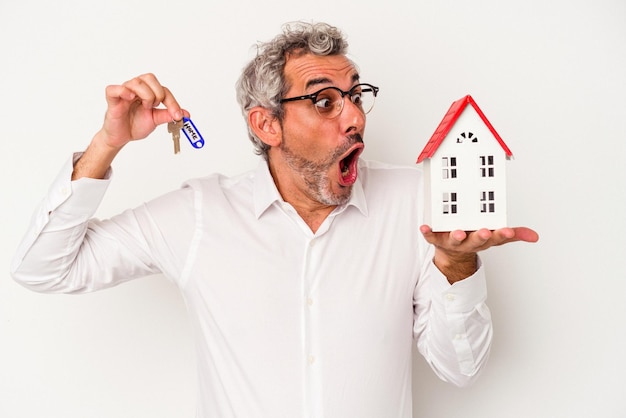 Iddle age business man holding clés et toy home isolé sur fond bleu