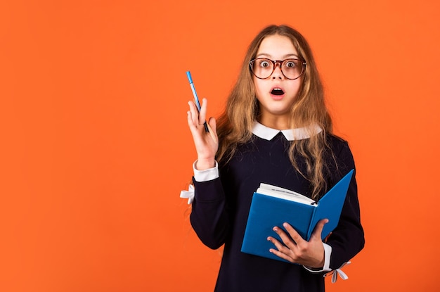 Idée créative. L'enfant surpris garde le stylo surélevé sur fond marron. La petite fille a eu une idée. Idée et créativité. L'école et l'éducation. Idée innovante. Apprendre. Pense. Créer. Génie au travail, espace occupé.