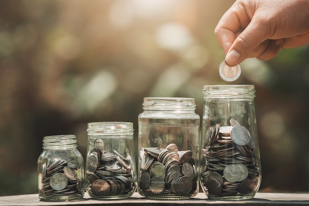 Idée d'économiser de l'argent à la main en mettant des pièces dans le verre de la cruche