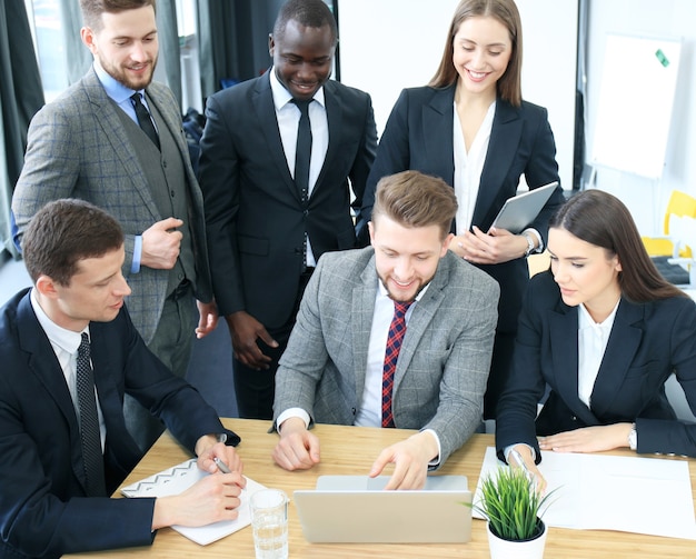 Idée de génie. Groupe de gens d'affaires regardant l'ordinateur portable ensemble. Une femme d'affaires regardant la caméra