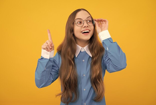 Idée intelligente Clever girl in eyeglasses fond jaune Enfant d'âge scolaire avec le doigt levé Eureka