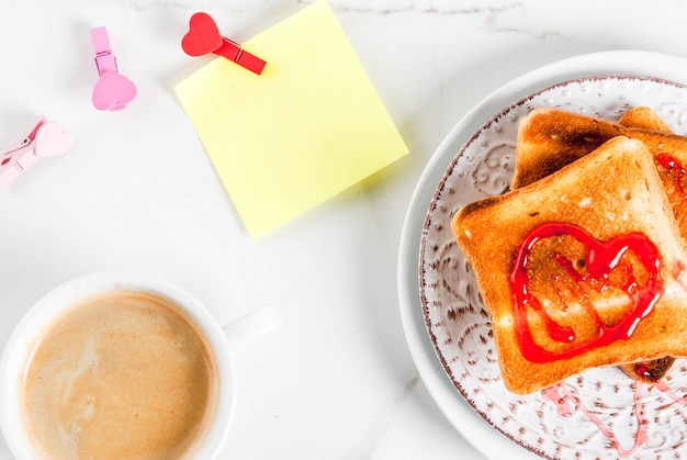 Idée de petit-déjeuner pour la Saint-Valentin avec une tasse de café, du pain grillé avec de la confiture de fraises rouges