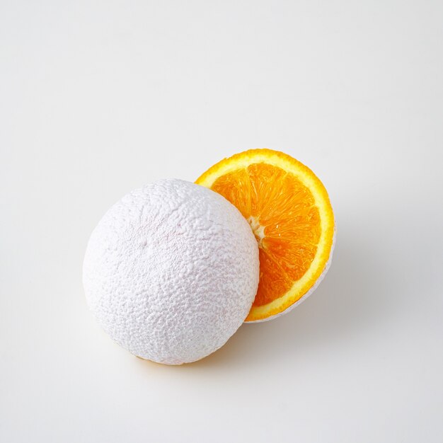 Idée surréaliste d'un fruit orange coupé blanc irréel sur un fond blanc.