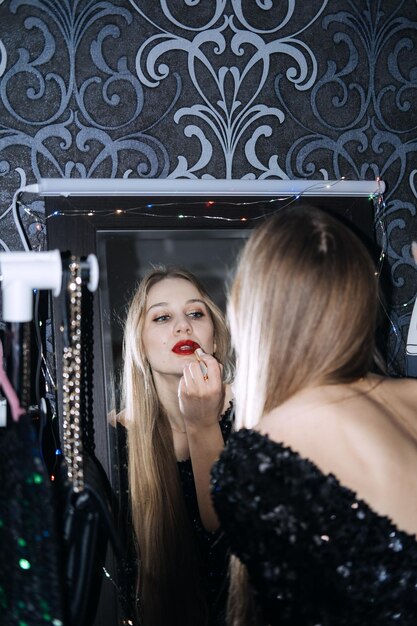 Idées de maquillage de réveillon du nouvel an belle jeune femme maquillage de soirée brillant lèvres rouges se prépare pour