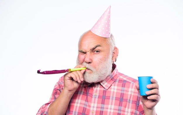 Idées pour les célébrations d'anniversaire des personnes âgées Homme grand-père barbu avec chapeau d'anniversaire et tasse de boisson Grand-père barbe grise soufflant un sifflet de fête Vieillir est toujours amusant Personnes âgées Concept d'anniversaire