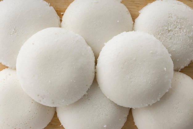 Idly ou Idli élément principal du petit-déjeuner du sud de l'Inde qui est magnifiquement disposé dans une base en bois avec un fond blanc