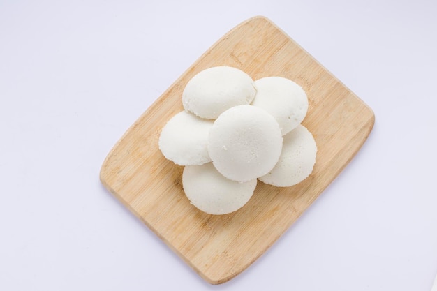 Idly ou Idli élément principal du petit-déjeuner du sud de l'Inde qui est magnifiquement disposé dans une base en bois avec un fond blanc