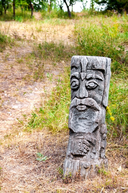 Idole en bois du dieu slave par un chemin dans la forêt