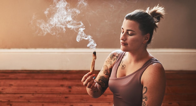 Il aide à améliorer la clarté et la concentration Photo d'une jeune femme brûlant un bâton de palo santo à la maison