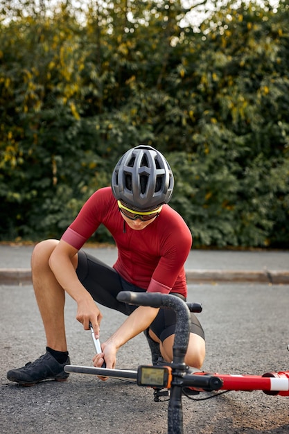 Il doit être réparé athlète jeune homme caucasien en tenue sportive et casque à l'aide d'un outil pendant la réparation...