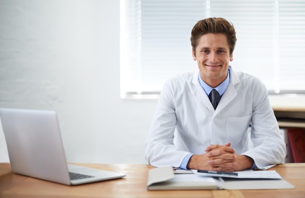 Il est confiant dans ses capacités médicales Portrait d'un médecin souriant assis à son bureau