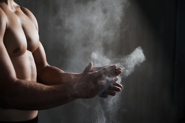 Il est prêt à tout donner. Une vue recadrée d'un gymnaste masculin saupoudrant ses mains de craie.