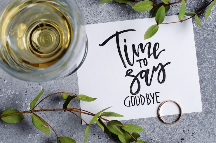 Photo il est temps de dire au revoir. l'inscription sur une feuille de papier blanc. vin blanc dans un verre. bague de fiançailles en or.