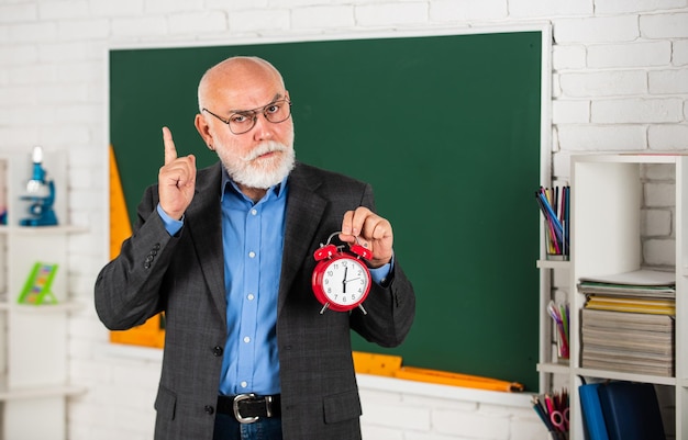 Il est temps d'étudier la discipline et la ponctualité l'enseignant principal tient le réveil la gestion du temps le début de la leçon l'examen commence maintenant le réveil le matin bonjour la rentrée scolaire