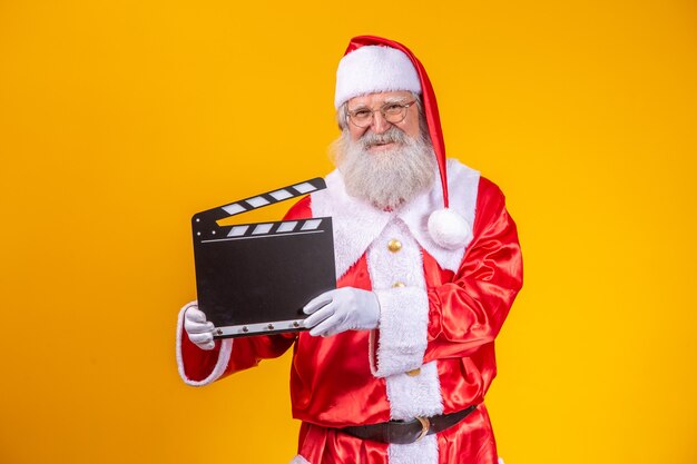 Il est temps de passer à l'action. Joyeux père Noël âgé posant avec un clap.