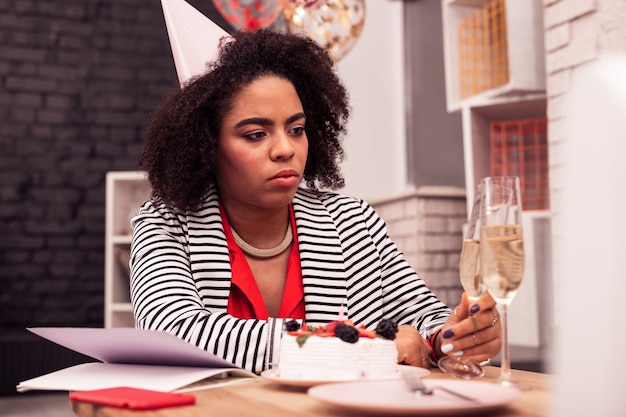 Il est temps de réfléchir. Belle femme adulte regardant le verre de champagne tout en pensant à sa vie