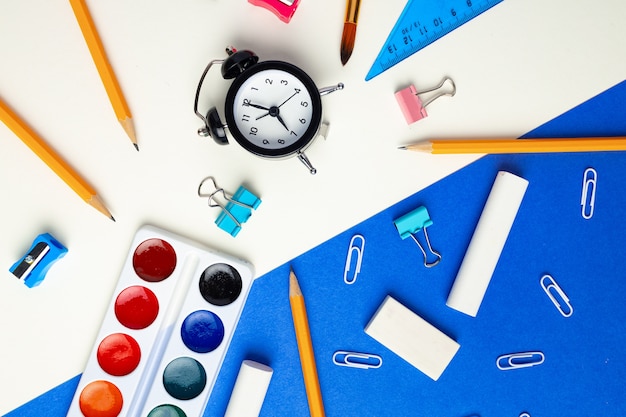 Il est temps de retourner à l'école. Vue de dessus de la papeterie et du réveil