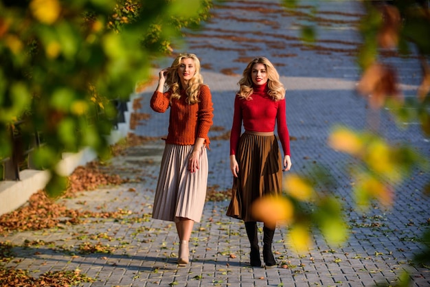 Il est temps de se détendre les filles en jupe ondulée et pull beauté féminine vraie féminité femmes d'automne en plein air amies promenade dans le parc journée ensoleillée avec des feuilles mortes saison de la mode d'automne Tendance plissée