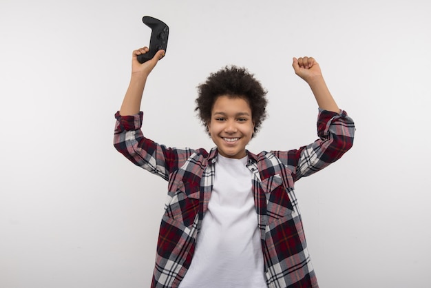 Il est temps de se détendre. Joyeux joyeux garçon applaudissant tout en tenant une console de jeux vidéo