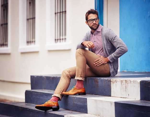 Il a intensifié son style Photo d'un beau jeune homme assis sur les marches