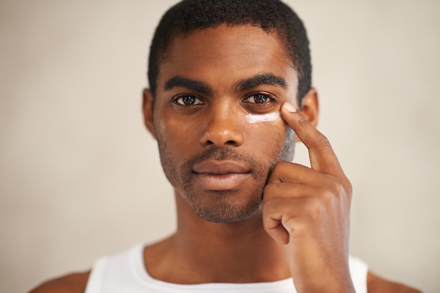 Il prend soin de sa peau Un jeune homme applique une crème pour le visage