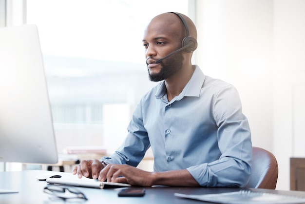 Il vous couvre Photo recadrée d'un beau jeune homme agent de centre d'appels travaillant sur son ordinateur au bureau