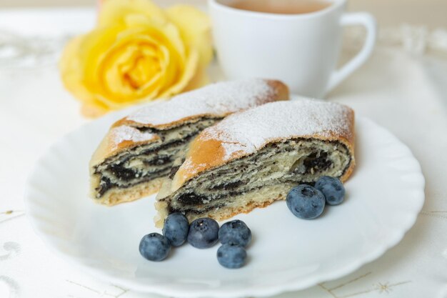 Il y a une assiette de gâteau aux graines de pavot sur la table et une tasse de thé à côté