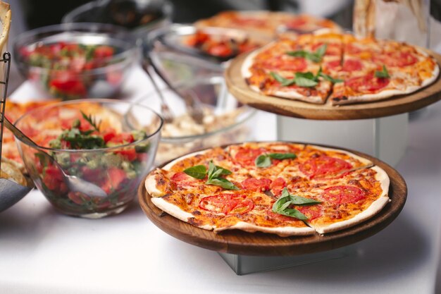 Il y a beaucoup de différentes pizzas fraîchement préparées sur la table du buffet