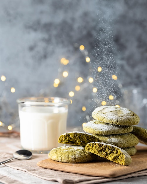 Photo il y a des biscuits faits maison avec du thé matcha sur une planche de bois il y a un verre de lait à côté