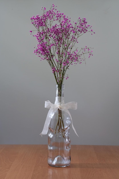 Il y a des fleurs séchées dans une bouteille sur la table.