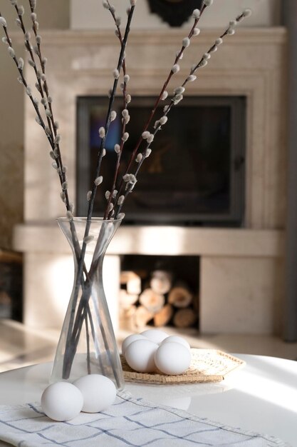 Photo il y a des œufs sur la table à côté d'un vase en verre contre le fond de la cheminée.