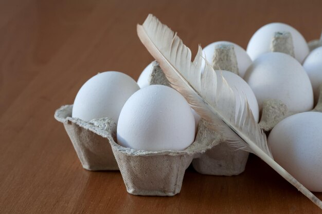 Il y a des œufs sur la table dans un plateau. A proximité se trouve une plume de poulet. focalisation locale.