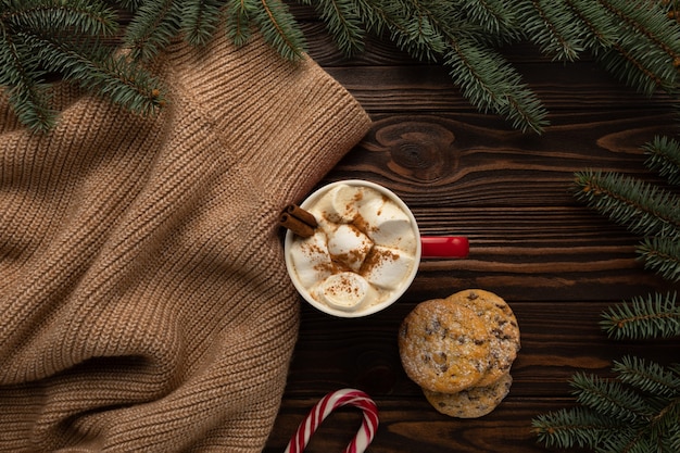 Il y a une tasse de chocolat chaud avec des guimauves et des biscuits faits maison sur la table avec un décor de Noël.