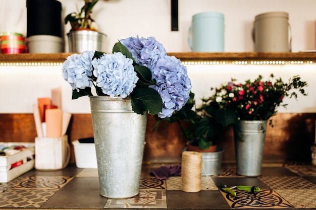 Il y a un vase avec de l'hortensia bleu clair sur la table du fleuriste.