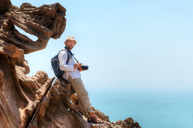 L'île d'Ormuz, Hormozgan, Iran, voyageur avec appareil photo est assis sur le bord de la falaise.