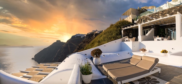 L'île de Santorin Oia coucher de soleil sur la scène de la caldeira deux chaises longues transats incroyable vue sur la mer des rayons du soleil