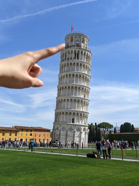 Photo illusion d'optique du doigt poussant la tour penchée de pise