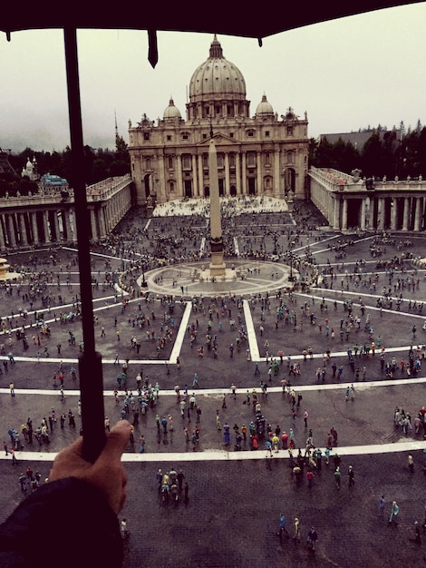 Photo illusion optique de la main tenant un parapluie sur les gens à la place saint-pierre