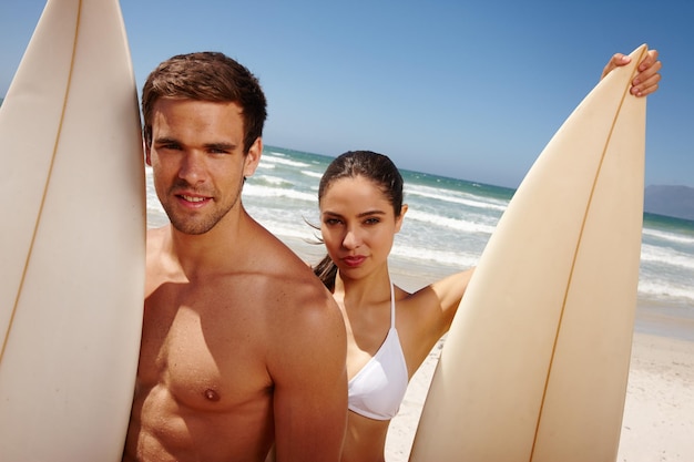 Ils forment une équipe méchante Photo d'un jeune couple tenant des planches de surf à la plage