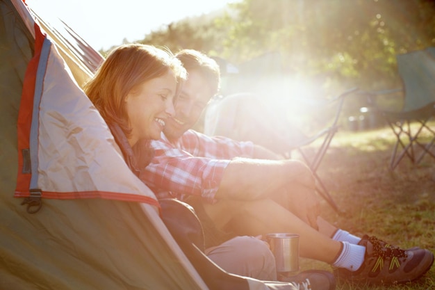 Ils partent toujours en camping Un jeune couple assis à l'entrée de leur tente