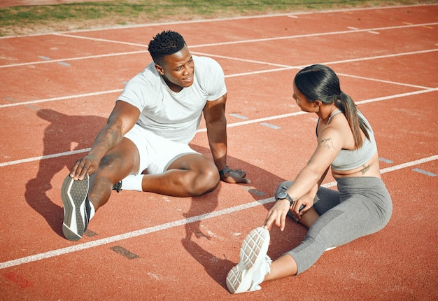 Ils s'échauffent à la tâche Prise de vue en grand angle d'un jeune couple athlétique s'échauffant avant de commencer leur routine d'exercice en plein air