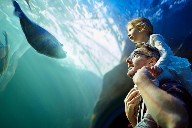 Ils se lient d'amitié avec tous les poissons Photo recadrée d'un père et de sa petite fille regardant une exposition dans un aquarium