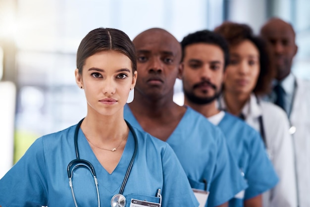 Photo ils sont les premiers dans le monde médical portrait d'un jeune groupe de médecins confiants se tenant les uns derrière les autres à l'intérieur d'un hôpital pendant la journée