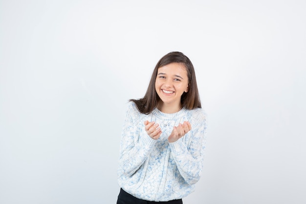 Image d'adolescente en pull debout et souriant joyeusement.