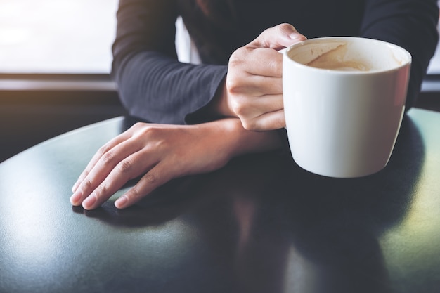 Image agrandi d&#39;une femme tenant et boire du café chaud au café